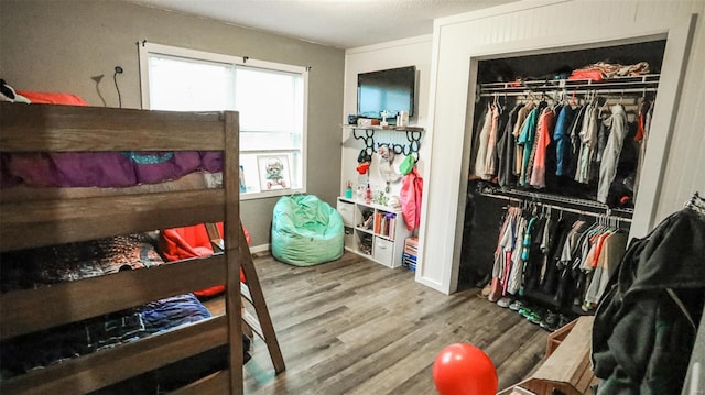 bedroom with wood finished floors and a closet