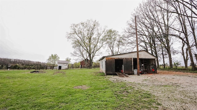 view of yard featuring an outdoor structure, fence, and an outbuilding