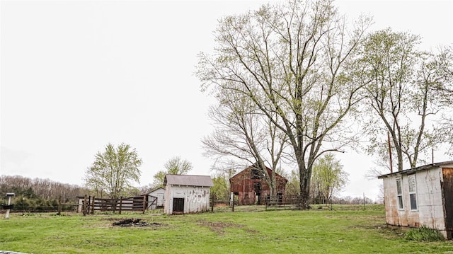 view of yard with a barn, fence, and an outbuilding
