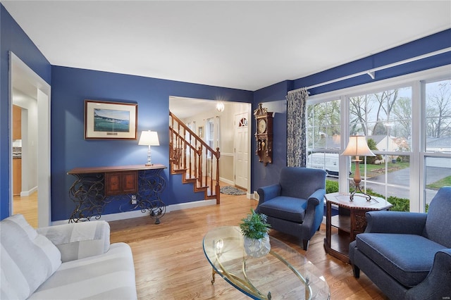 living area with baseboards, wood finished floors, and stairs