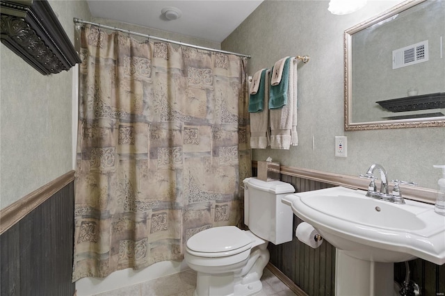 full bath featuring visible vents, a sink, tile patterned floors, toilet, and a wainscoted wall
