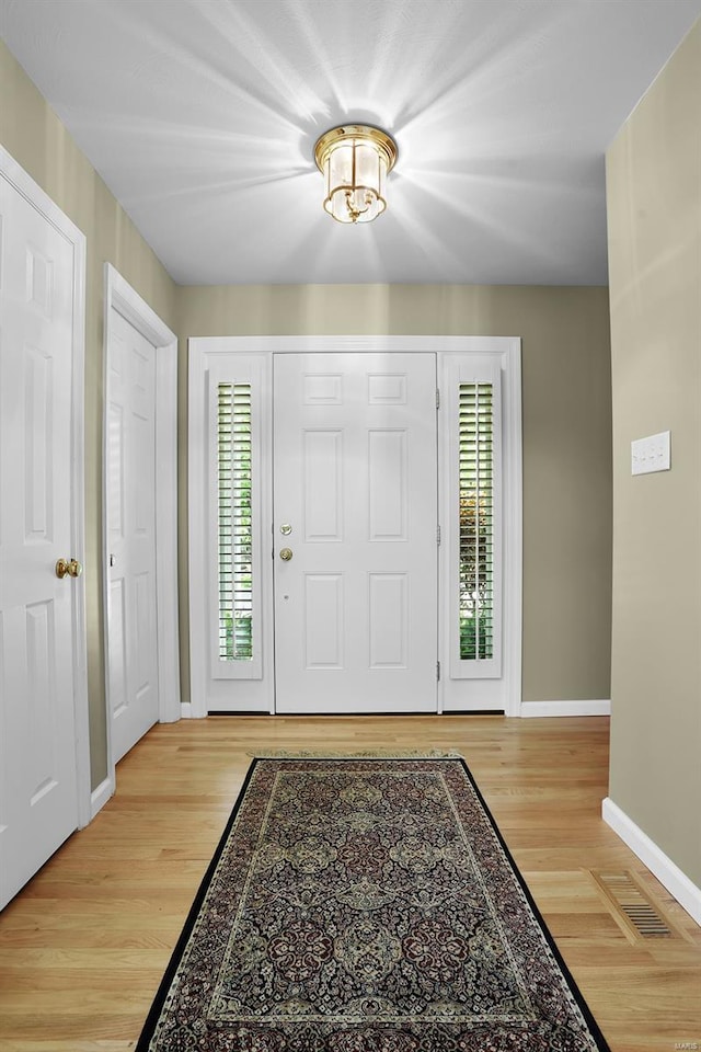 entryway with baseboards, wood finished floors, and visible vents