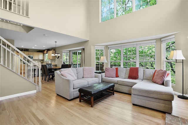 living area with stairway, a high ceiling, and light wood-type flooring