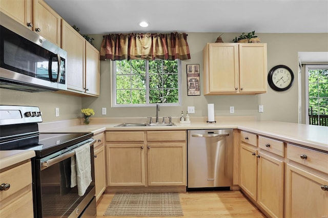 kitchen featuring a sink, light brown cabinets, stainless steel appliances, and light wood-type flooring