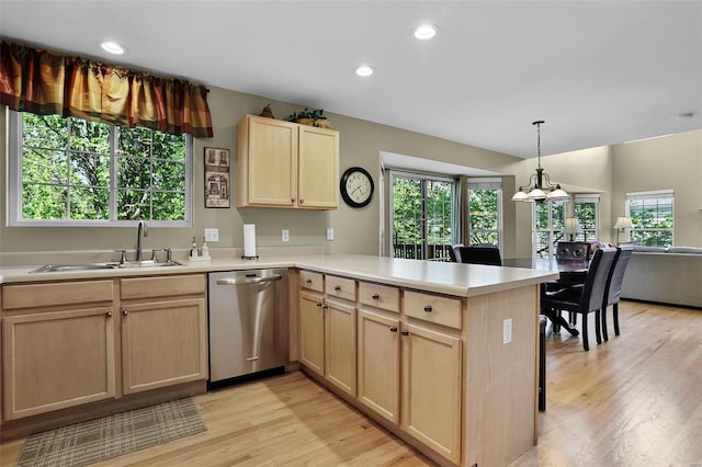 kitchen featuring light countertops, light brown cabinets, stainless steel dishwasher, and a peninsula