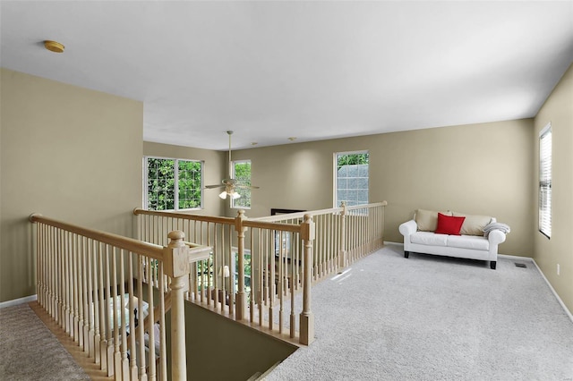 living area with carpet flooring, ceiling fan, visible vents, and baseboards