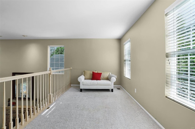 living area featuring baseboards, carpet flooring, and a wealth of natural light