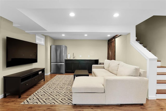 living room with indoor wet bar, baseboards, stairs, and wood finished floors