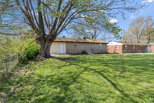 rear view of house with central air condition unit, a yard, and a fenced backyard