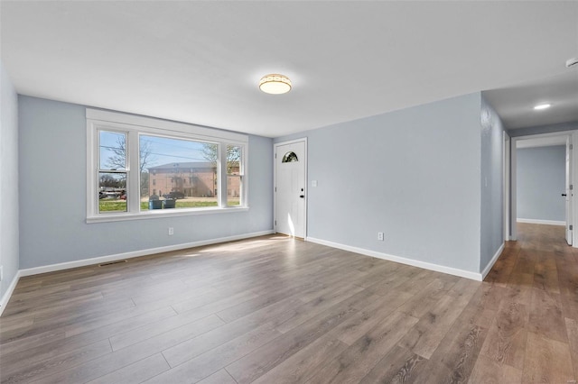 empty room featuring wood finished floors, baseboards, and visible vents