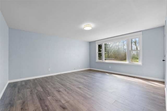 unfurnished room featuring wood finished floors, baseboards, and visible vents