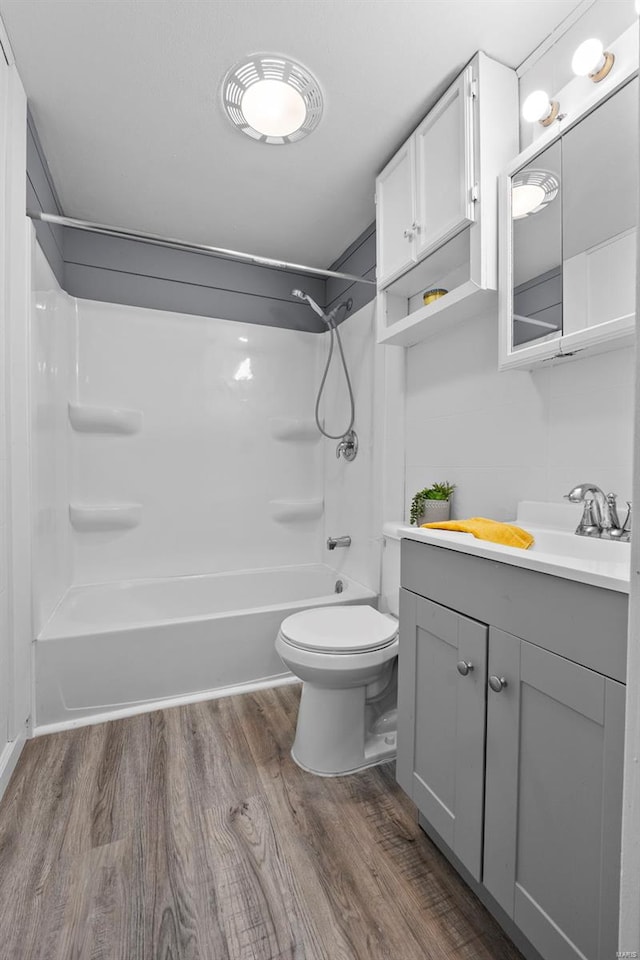 full bath featuring toilet, shower / washtub combination, wood finished floors, and vanity