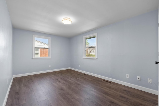 unfurnished room with visible vents, baseboards, and dark wood finished floors