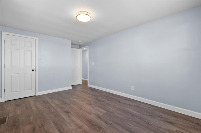 unfurnished bedroom with baseboards, dark wood-style floors, and visible vents