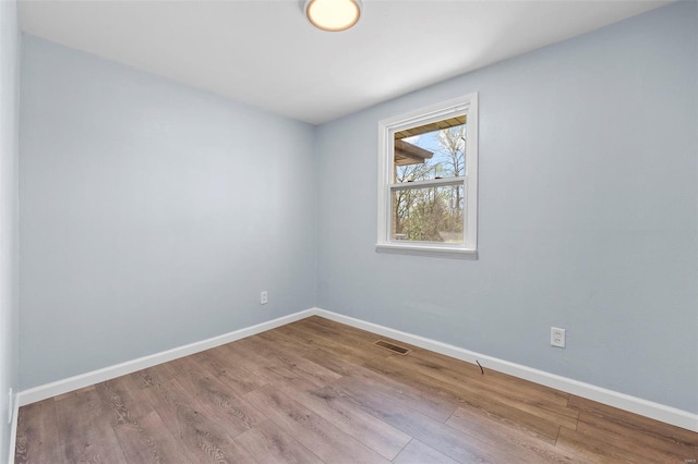 unfurnished room with visible vents, baseboards, and wood finished floors