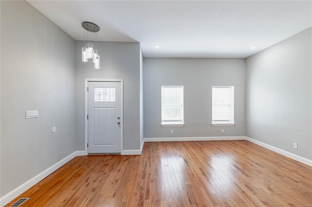 foyer with baseboards, an inviting chandelier, visible vents, and light wood-type flooring