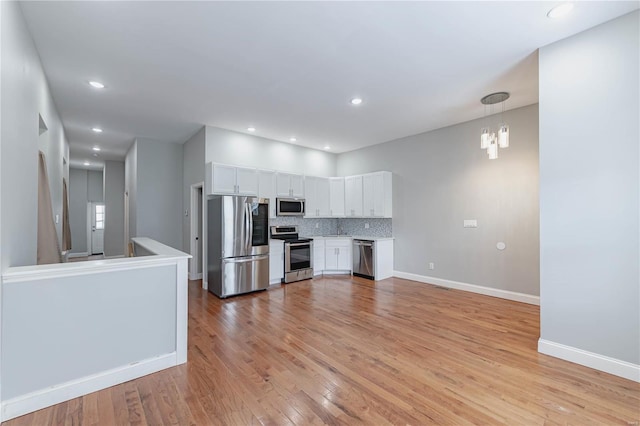 kitchen featuring white cabinets, light countertops, stainless steel appliances, baseboards, and light wood-type flooring