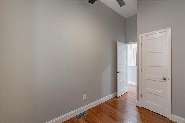 empty room with visible vents, a ceiling fan, baseboards, and wood finished floors