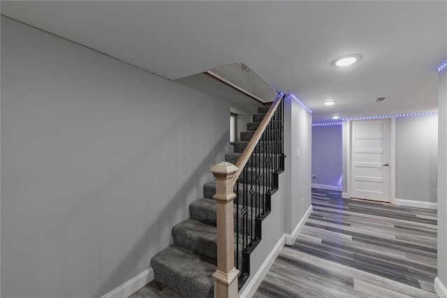 staircase featuring baseboards, wood finished floors, and visible vents