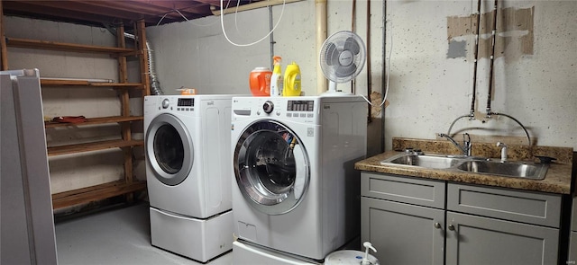 clothes washing area featuring washer and clothes dryer, a sink, and cabinet space