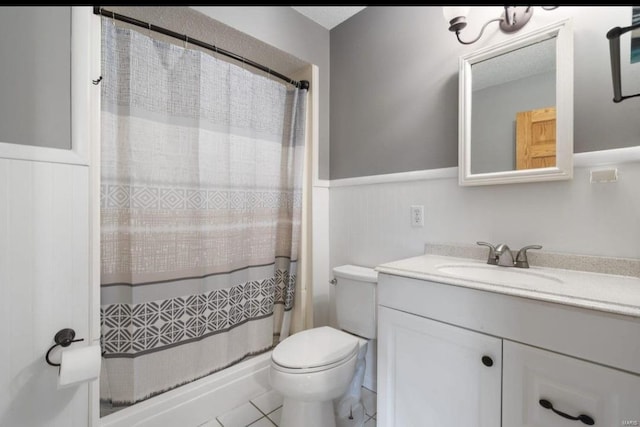 full bath featuring toilet, vanity, a shower with curtain, and a wainscoted wall