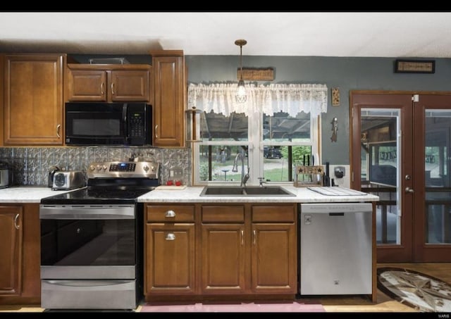 kitchen featuring french doors, light countertops, brown cabinetry, stainless steel appliances, and a sink