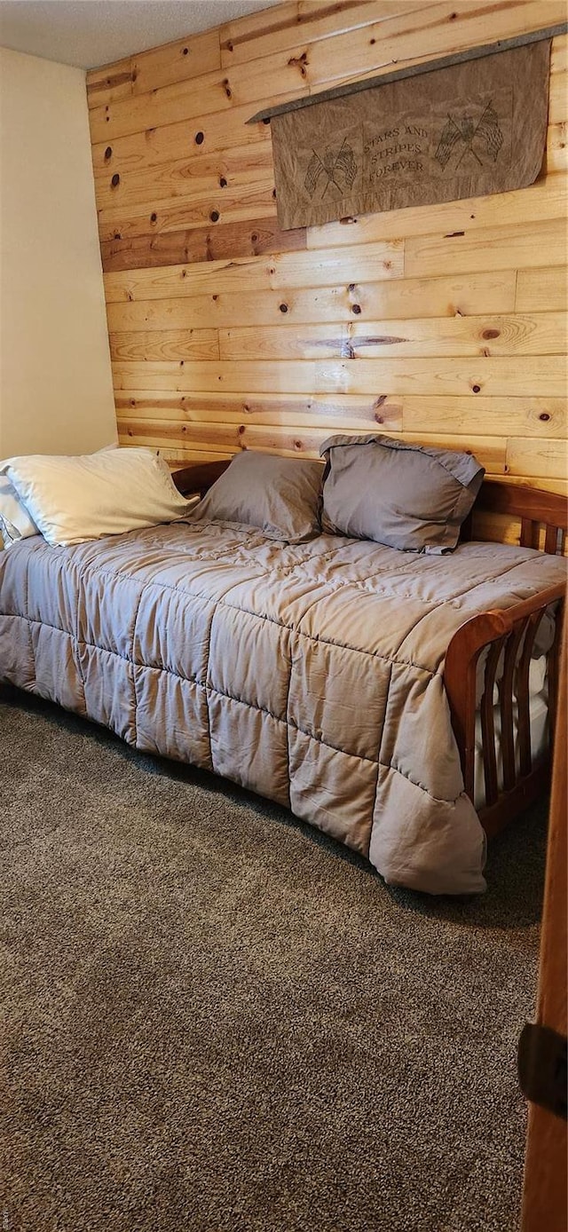carpeted bedroom featuring wood walls