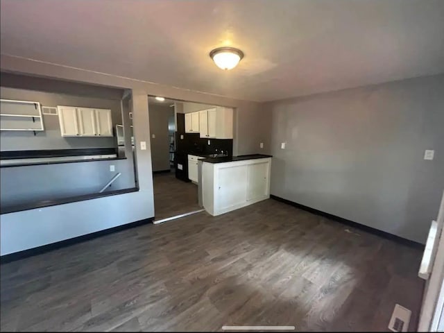 kitchen featuring dark wood-style flooring, dark countertops, white cabinetry, and baseboards