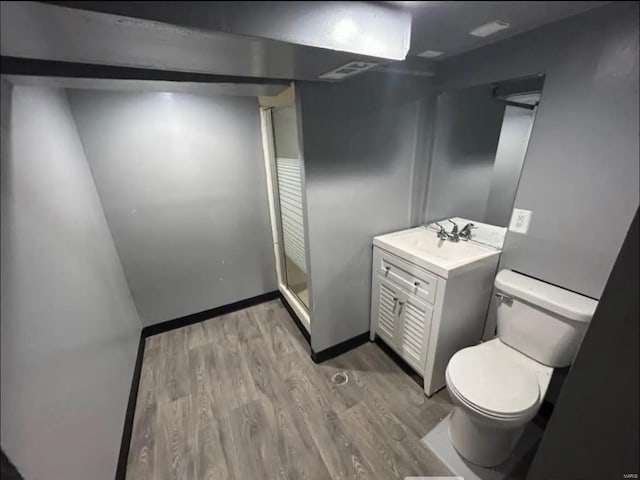 bathroom with a shower stall, vanity, visible vents, toilet, and wood finished floors