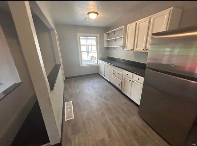 kitchen featuring visible vents, open shelves, dark countertops, freestanding refrigerator, and wood finished floors