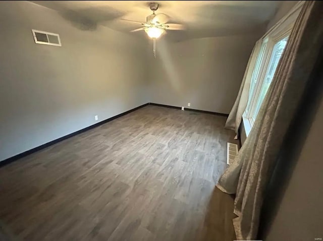 spare room with visible vents, baseboards, a ceiling fan, and wood finished floors