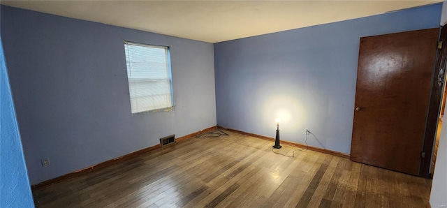 empty room with baseboards, wood-type flooring, and visible vents