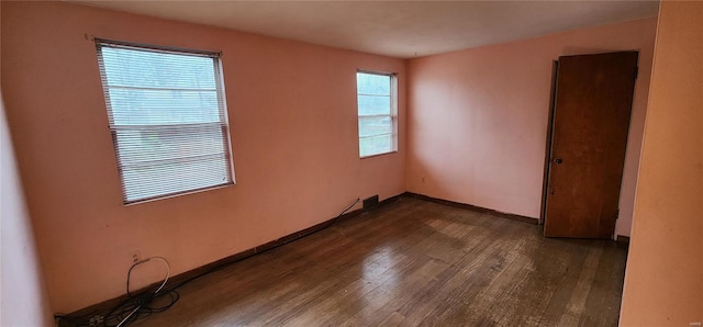 empty room with dark wood-style flooring and baseboards