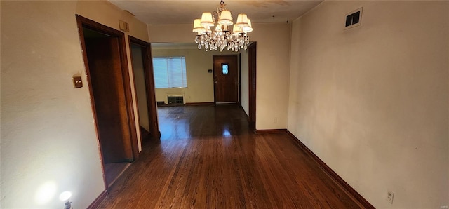 corridor featuring dark wood-type flooring, visible vents, baseboards, and an inviting chandelier