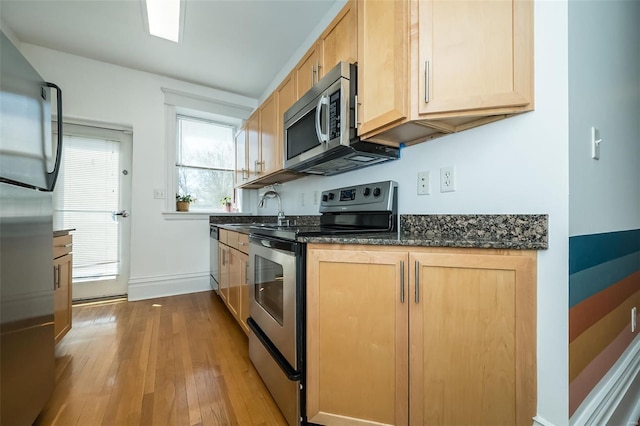 kitchen with a sink, light brown cabinetry, and stainless steel appliances