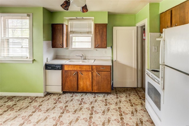 kitchen with a sink, white appliances, light countertops, brown cabinetry, and backsplash