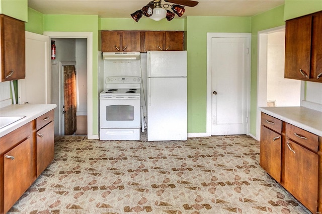 kitchen featuring white appliances, brown cabinets, under cabinet range hood, and light countertops