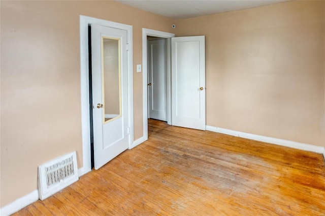 unfurnished room with visible vents, baseboards, and wood finished floors