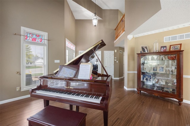 sitting room featuring a towering ceiling, baseboards, wood finished floors, and visible vents