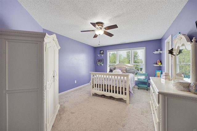 bedroom with baseboards, a textured ceiling, light carpet, and ceiling fan