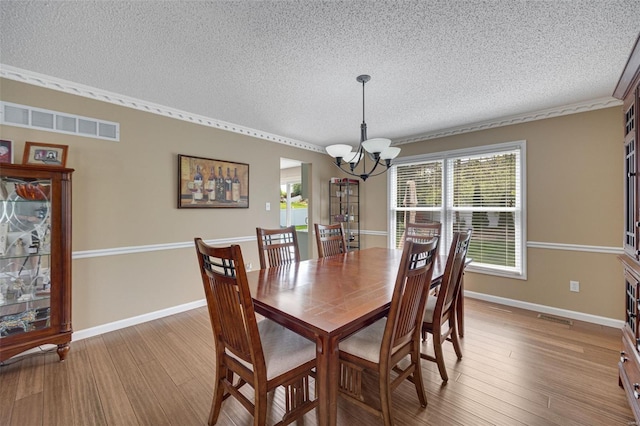 dining room with visible vents, light wood-style floors, plenty of natural light, a textured ceiling, and a notable chandelier