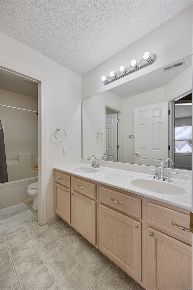bathroom with double vanity, toilet, visible vents, and a sink