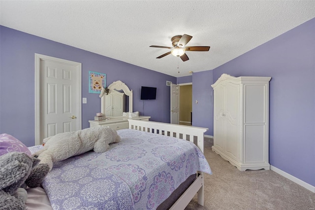 bedroom with ceiling fan, carpet floors, baseboards, and a textured ceiling