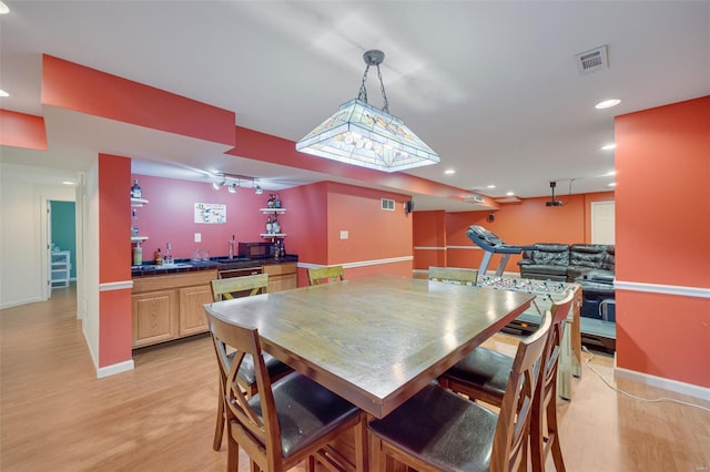 dining area featuring visible vents, baseboards, recessed lighting, wet bar, and light wood finished floors