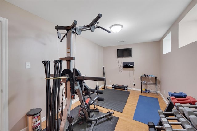 exercise room with baseboards and wood finished floors