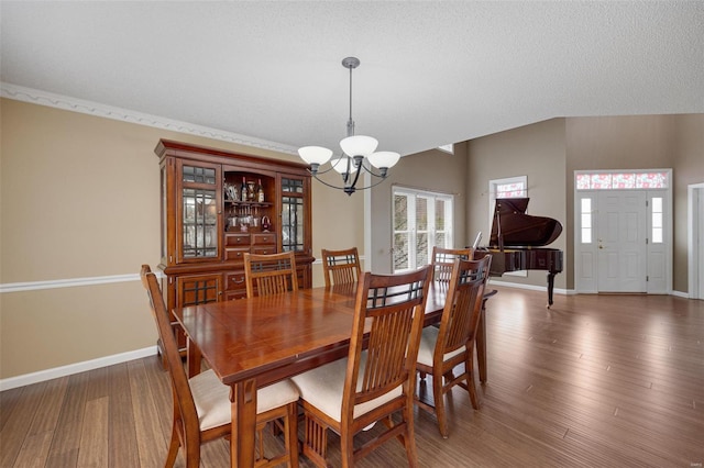 dining space featuring baseboards, a notable chandelier, and wood finished floors