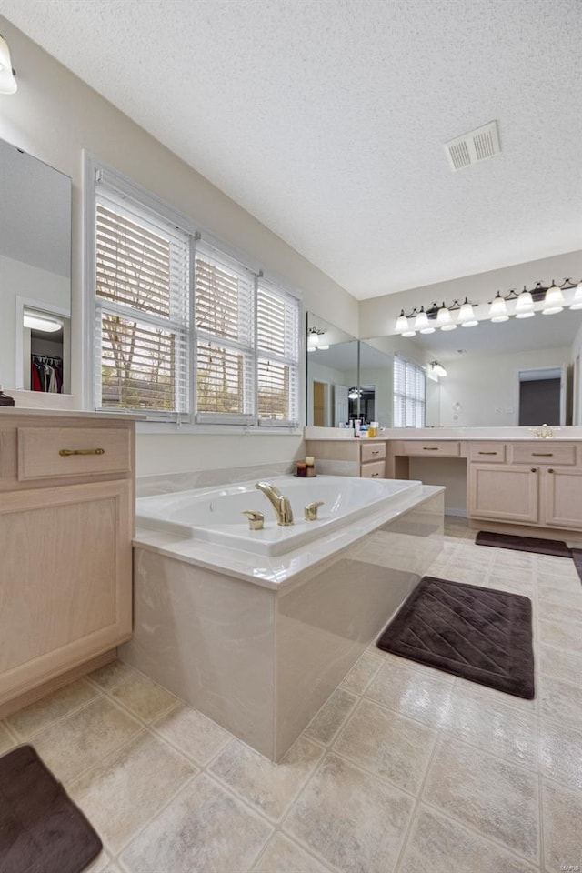 full bath featuring visible vents, vanity, a textured ceiling, tile patterned floors, and a bath