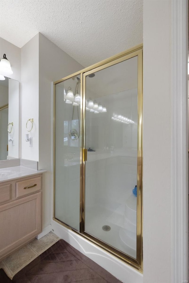 bathroom featuring vanity, a shower stall, and a textured ceiling