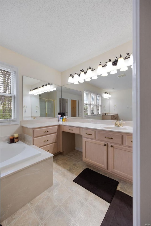 full bathroom with a garden tub, a textured ceiling, a wealth of natural light, and vanity