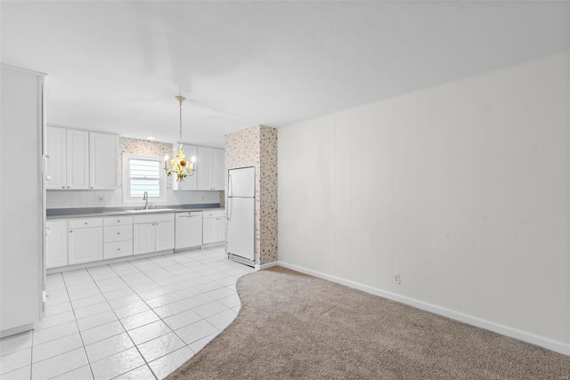 kitchen featuring decorative light fixtures, a sink, white cabinets, a notable chandelier, and white appliances